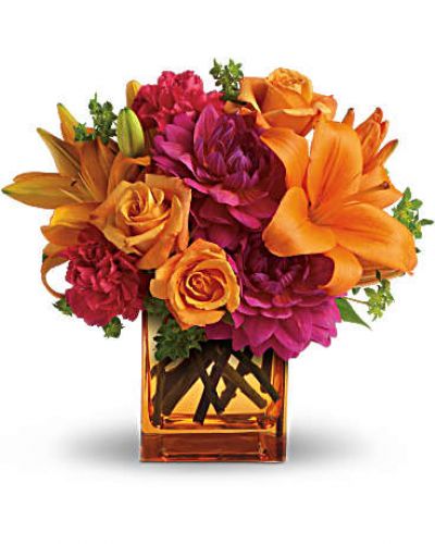 <p>Feeling hot, hot, hot! This sizzling summer floral arrangement mixes hot pink dahlias and carnations with bright orange roses and lilies in an orange cube vase. It’s the floral equivalent of a trip to Miami in July!<br />
Light orange roses, orange asiatic lilies, hot pink dahlias and hot pink carnations are presented with fresh green bupleurum in an orange glass cube vase.</p>