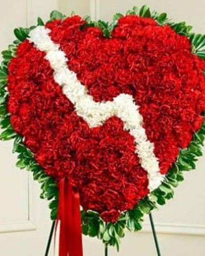 <p>Express your deepest feelings of love at this difficult time with this poignant heart-shaped sympathy arrangement. This standing spray arrangement is created from fresh red carnations, white carnations and variegated pittosporum, and accented with satin ribbon. Traditionally sent directly to the funeral home by family members and displayed on a stand.</p>