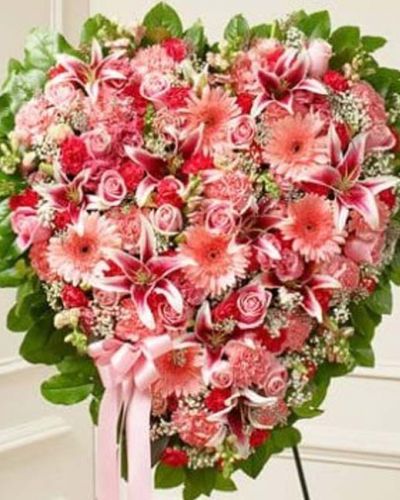 <hr />
<p>This solid heart standing spray is a beautiful symbol of your sympathy and support. Featuring pink flowers such as roses, stargazer lilies, Gerbera daisies, carnations and more, it is tied to a wire easel with satin ribbon. Traditionally sent directly to the funeral home by family and friends.</p>