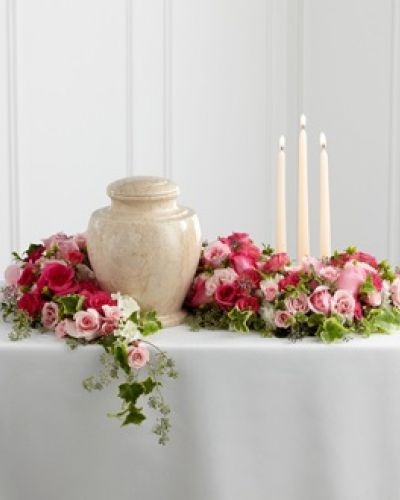 <p>The FTD® Remembrance® Arrangement is a sweetly sophisticated way to display their urn at their final farewell service. Fuchsia and pale pink roses and spray roses are accented with lush greens to form an exquisite arrangement that winds around the base of the urn and curls around 3 ivory taper candles, creating a warm and comforting presentation that commemorates a life that brought kindness and beauty in to the lives of others.</p>