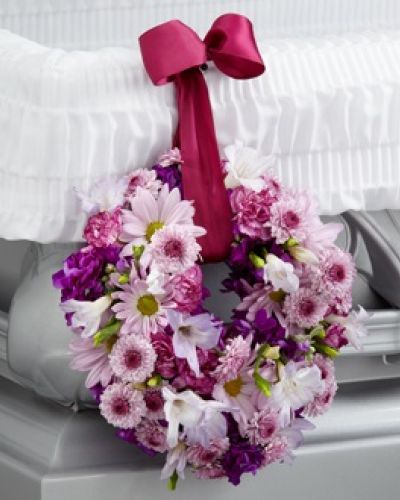 <p>The FTD® Thoughts & Prayers™ Wreath Adornment is a sweet accent to symbolize your love and affection for the deceased. Lavender carnations, freesia, daisies and button poms are accented with deep magenta stock and arranged to form a 6-inch wreath which hangs from the side of the casket from a burgundy wired ribbon.</p>